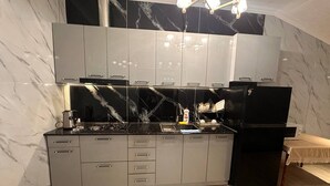A modern kitchen with a marble backsplash, stainless steel appliances, and a wooden floor.