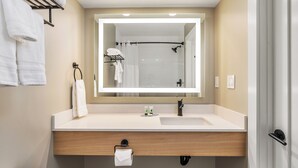 A modern bathroom with a large mirror, a sink, and a towel rack.
