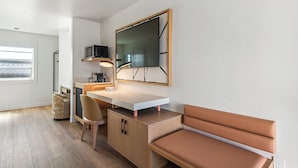 A modern room with a desk, chair, bench, and a large mirror.