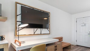 A modern room with a desk, chair, and a large mirror.