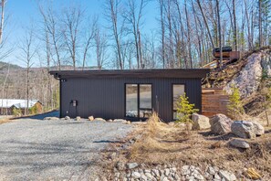 A small, dark-colored cabin with a gravel driveway and a wooden deck. - Rockhaus-Cliffside Dome Sauna/Hot Tub/Tremblant (La Conception)