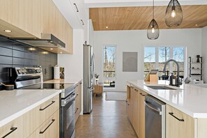 Eine moderne Küche mit Edelstahlgeräten, Holzschränken und großen Fenstern.