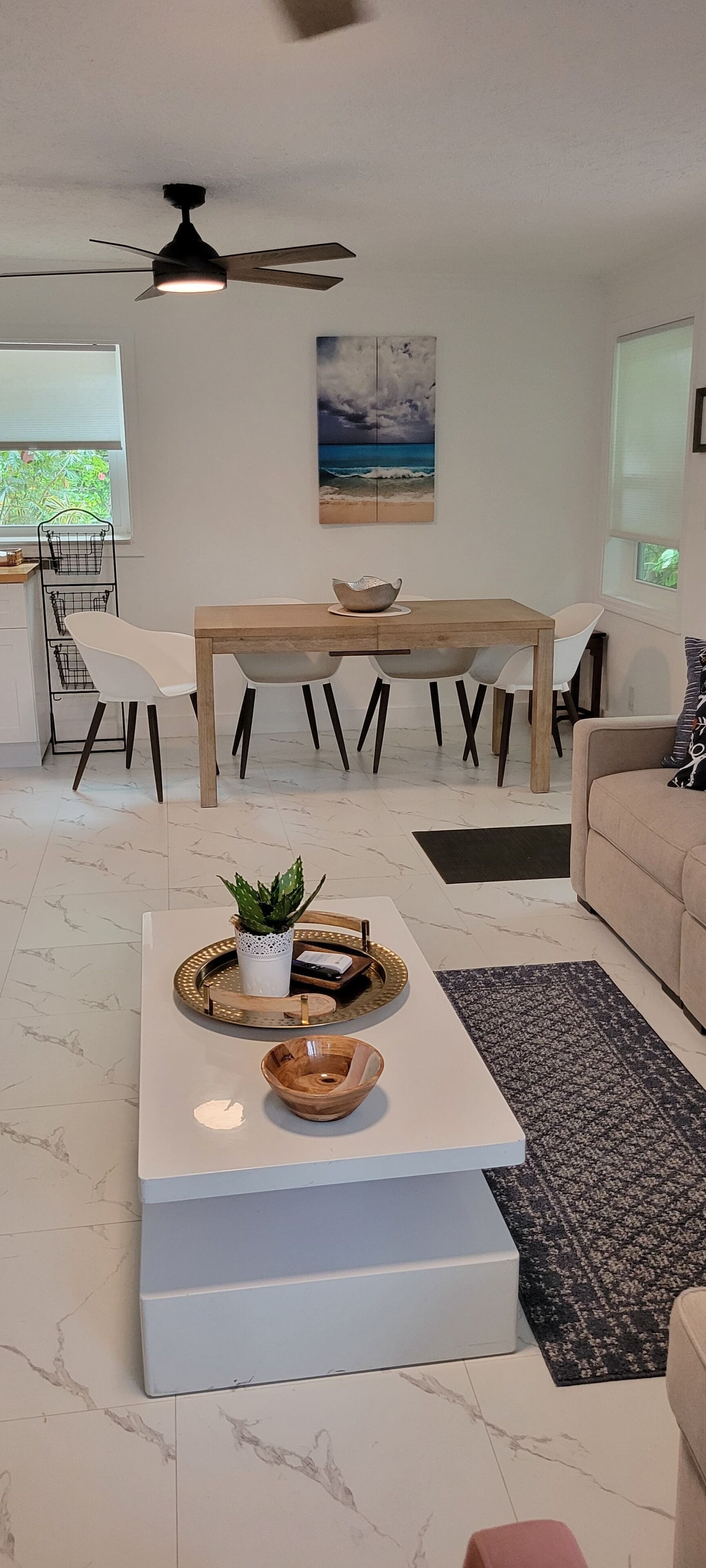 A modern living room with a white coffee table, a dining table, and a sofa.
