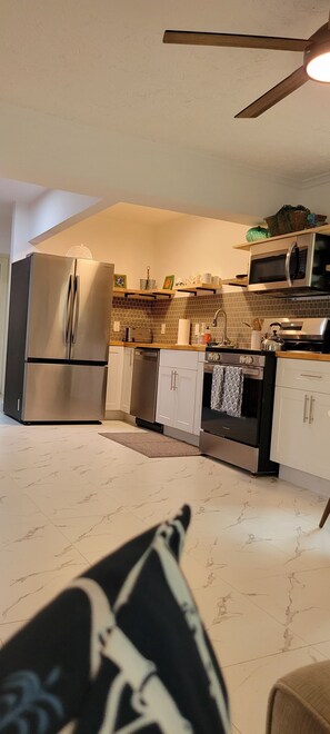 A modern kitchen with stainless steel appliances, a microwave, and a ceiling fan. - “No worries “ (Pompano Beach)