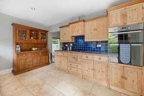 A kitchen with wooden cabinets, a tiled backsplash, and stainless steel appliances. - Beautiful Secluded 2 Bedroom Coach House (Nottingham)