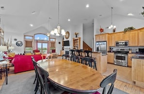 A spacious living area with a large wooden dining table surrounded by chairs, a red sofa, and a kitchen with wooden cabinets and stainless steel appliances. - Sunkissed (Avon)