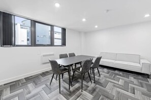 Ein modernes Hotelzimmer mit großem Fenster, einem Esstisch mit Stühlen und einem Sofa.
