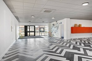A spacious interior with a patterned floor, a large open door leading outside, and a wall-mounted orange rack.