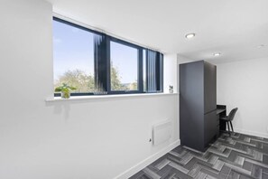 A modern room with a large window, a radiator, a desk, and a chair. - Brand New Spacious Studio in Beeston (Beeston)