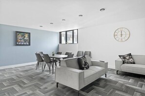A modern room with a dining table, chairs, a sofa, and a clock on the wall. - Brand New Spacious Studio in Beeston (Beeston)
