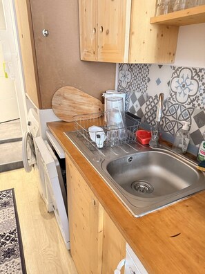 A kitchen with wooden cabinets, a stainless steel sink, and a dish rack. - Le cocon des Capucins (Lyon)