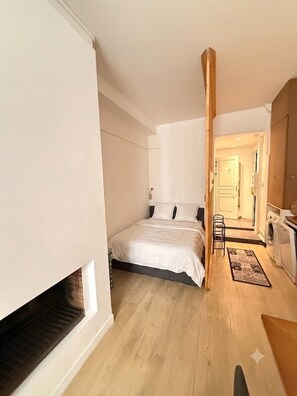 A bedroom with a bed, a washing machine, and a small hallway. - Le cocon des Capucins (Lyon)