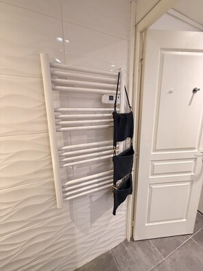A white door with a handle, a white radiator, and a black bag hanging on the radiator. - Le cocon des Capucins (Lyon)
