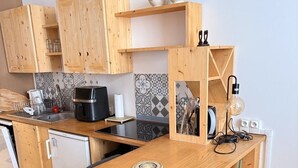 Kompakti keittiö, jossa on puukaapit, sisäänrakennettu liesi ja pieni pesuallas.