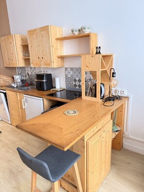 A compact kitchen with wooden cabinets, a built-in stove, and a small sink. - Le cocon des Capucins (Lyon)