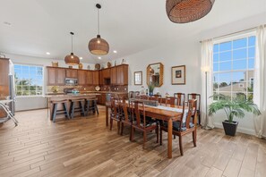 A spacious kitchen with wooden cabinets, a central island, and pendant lighting. - Tranquil Tides (New Smyrna Beach)