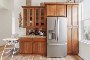 Una cocina con armarios de madera, un refrigerador de acero inoxidable, una cafetera y una trona.