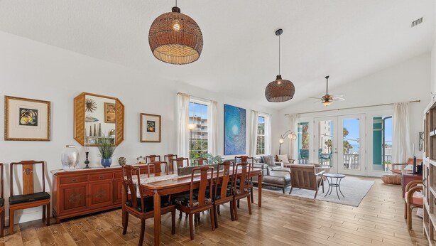 A spacious dining area with a wooden table and chairs, a large window with a view, and a ceiling fan. - Tranquil Tides (New Smyrna Beach)