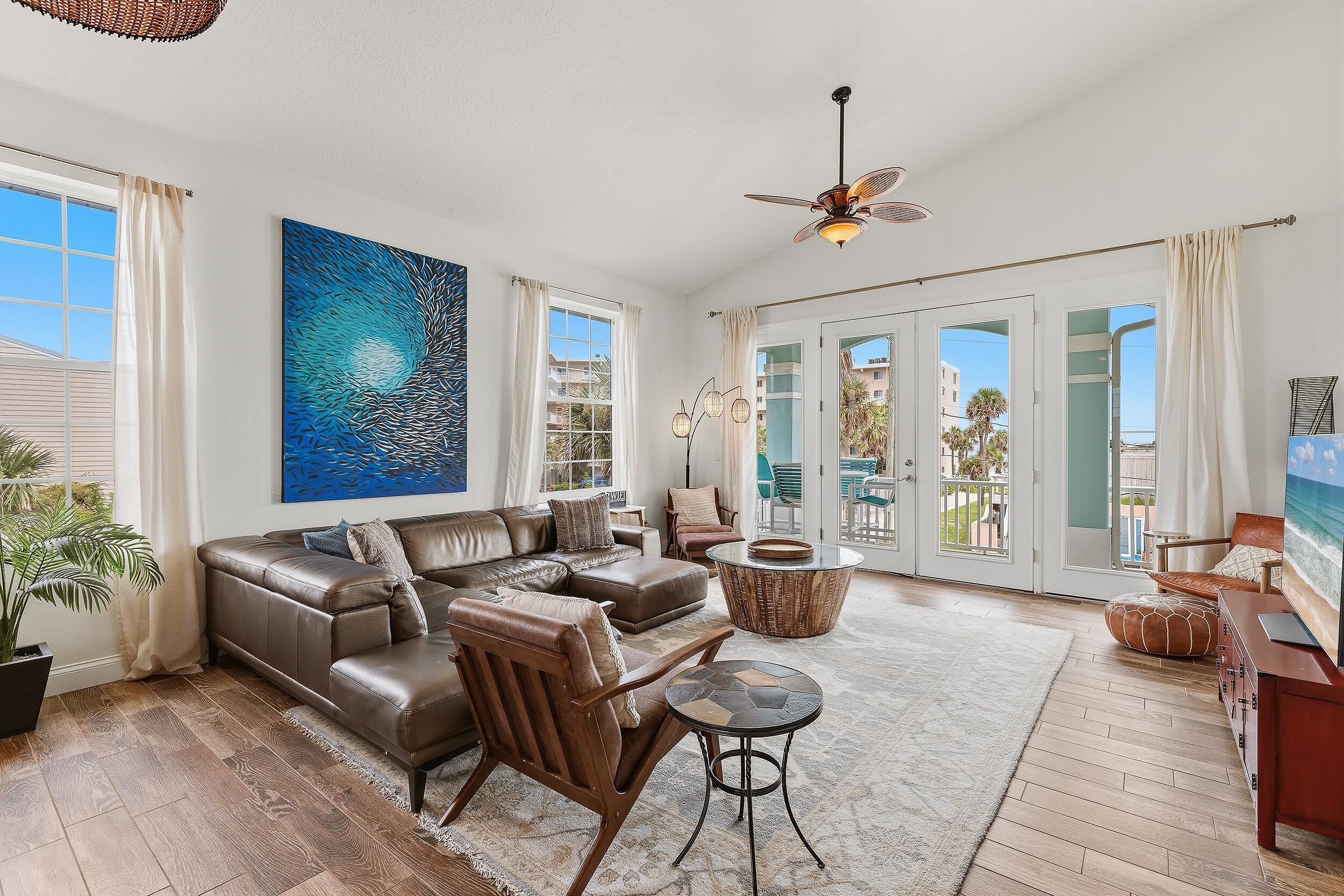 A spacious living room with a large sectional sofa, a round coffee table, and a ceiling fan.