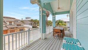 A covered outdoor area with a wooden table and chairs, a white railing, and a view of neighboring houses. - Tranquil Tides (New Smyrna Beach)