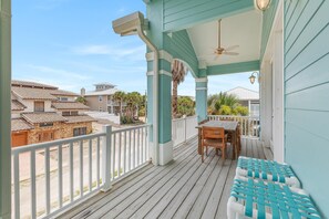 A covered outdoor area with a wooden table and chairs, a white railing, and a view of neighboring houses. - Tranquil Tides (New Smyrna Beach)