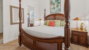 A four-poster bed with a wooden headboard and a white quilted bedspread. - Tranquil Tides (New Smyrna Beach)