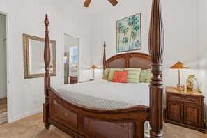 A four-poster bed with a wooden headboard and a white quilted bedspread. - Tranquil Tides (New Smyrna Beach)