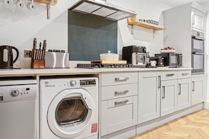 A modern kitchen with a built-in washer and dryer, a microwave, and a toaster. - Luxurious 3 Bedroom Apartment in Park Estate (Nottingham)