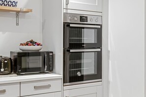 A kitchen with a built-in oven, a microwave, and a toaster. - Luxurious 3 Bedroom Apartment in Park Estate (Nottingham)