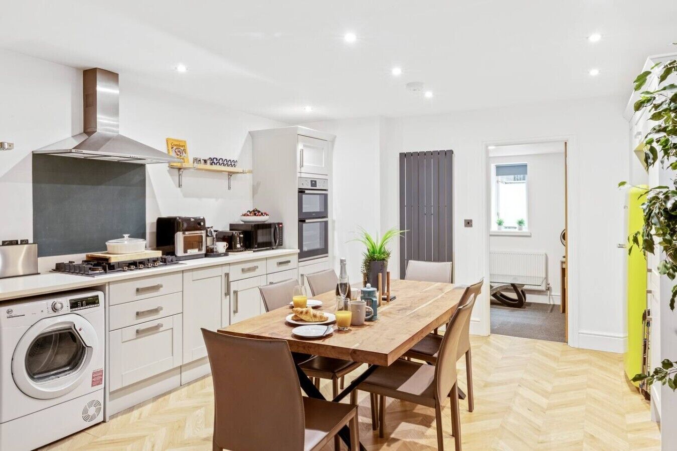 A modern kitchen with a dining area, equipped with appliances like a microwave, oven, and washing machine.