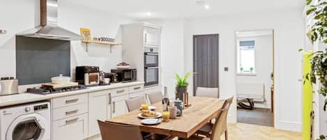 A modern kitchen with a dining area, equipped with appliances like a microwave, oven, and washing machine.