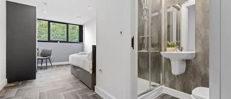 A modern bathroom with a shower, toilet, and a sink mounted on the wall.