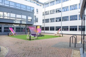 A courtyard with a brick floor, surrounded by modern buildings with large windows.