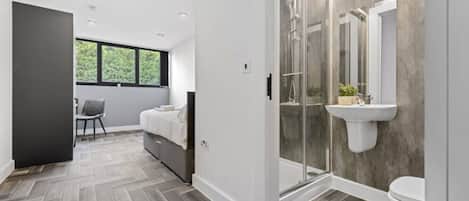 A modern bathroom with a shower, toilet, and a sink mounted on a concrete wall.