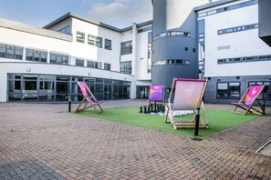 A courtyard with a chessboard, outdoor seating, and modern buildings.