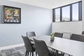 Una sala de conferències amb un gran taulell, sis cadires, una planta en test i un quadre amb marc a la paret.