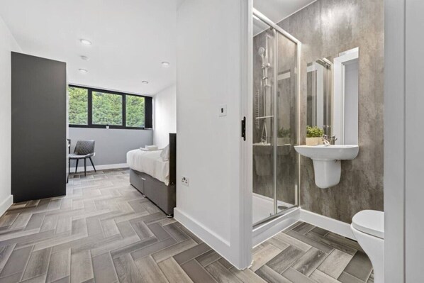 A modern bathroom with a shower, toilet, and a sink mounted on a concrete wall.