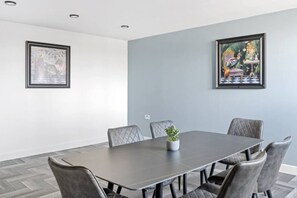 A conference room with a rectangular table, six chairs, and two framed artworks on the walls. - Brand New Spacious Studio in Beeston (Beeston)