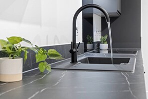 A modern kitchen with a sleek black faucet, a marble countertop, and a potted plant.