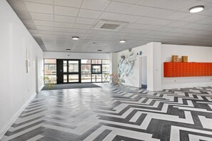 A spacious interior with a patterned floor, a door leading outside, and a wall with a graffiti-style mural.