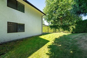 A modern two-story building with a white exterior, a well-maintained lawn, and a large tree providing shade. - East Abbotsford Spanish Villa (Abbotsford)