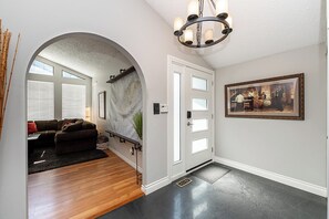 A hallway with a wooden floor, a white door, and a framed picture on the wall. - East Abbotsford Spanish Villa (Abbotsford)