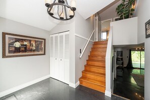 A staircase with wooden steps leading to a second floor, a white door with louvered shutters, and a framed picture on the wall. - East Abbotsford Spanish Villa (Abbotsford)