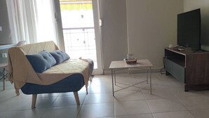 A living room with a sofa, a coffee table, a television, and a sliding door.
