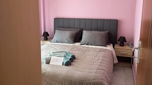 A bedroom with a bed, pillows, a bedside table, a lamp, and a sign on the bed.