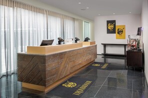 A hotel reception desk with a modern design, a check-in counter, and a wall-mounted information board. - Modern Stay in Downtown New Orleans Near the Quarter l 2 Units (New Orleans)