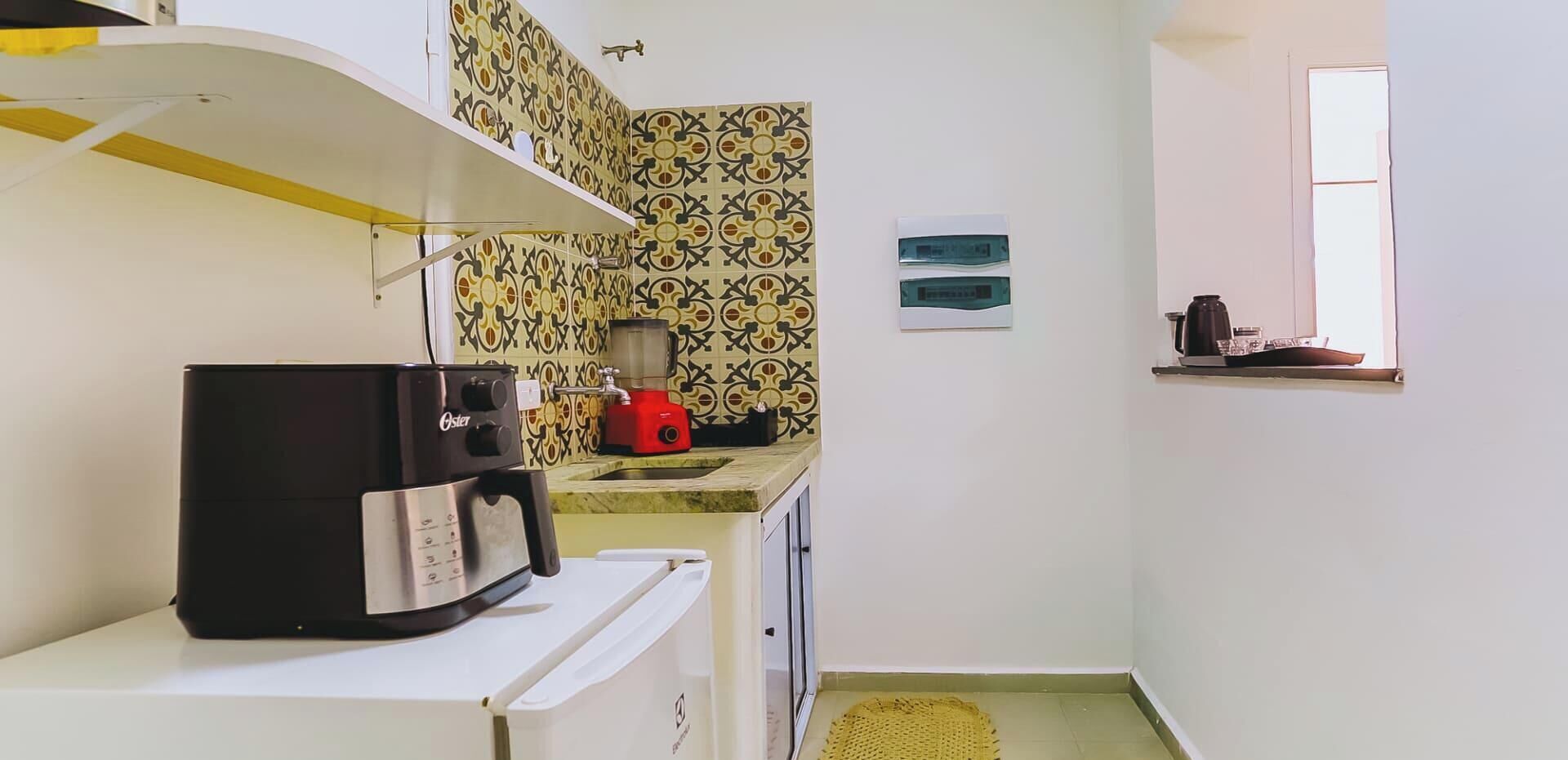 Uma cozinha compacta com cafeteira, liquidificador e uma janela.