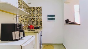 Una cocina compacta con cafetera, licuadora y ventana.