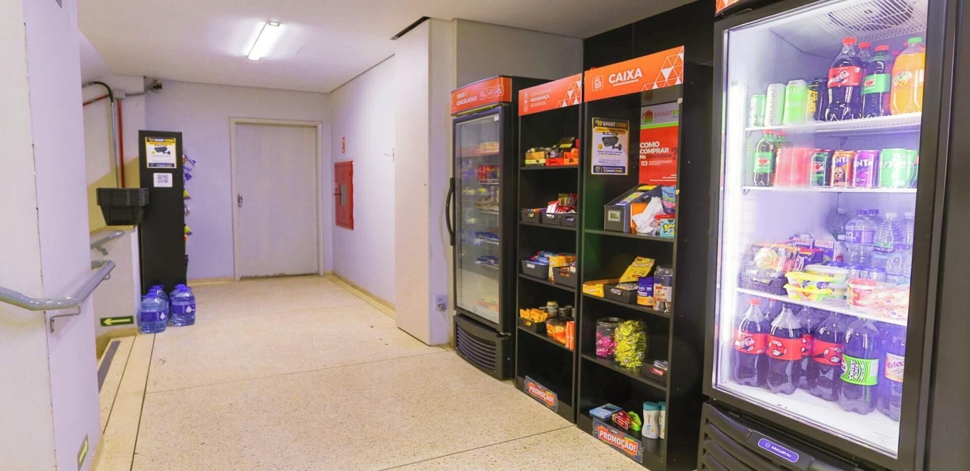 A corridor with vending machines and a refrigerator stocked with beverages.