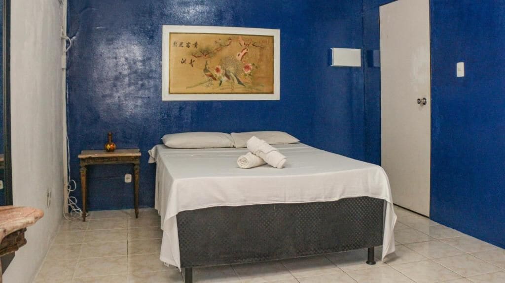 Une chambre à coucher avec un lit, une table de chevet, un tableau au mur et une porte.